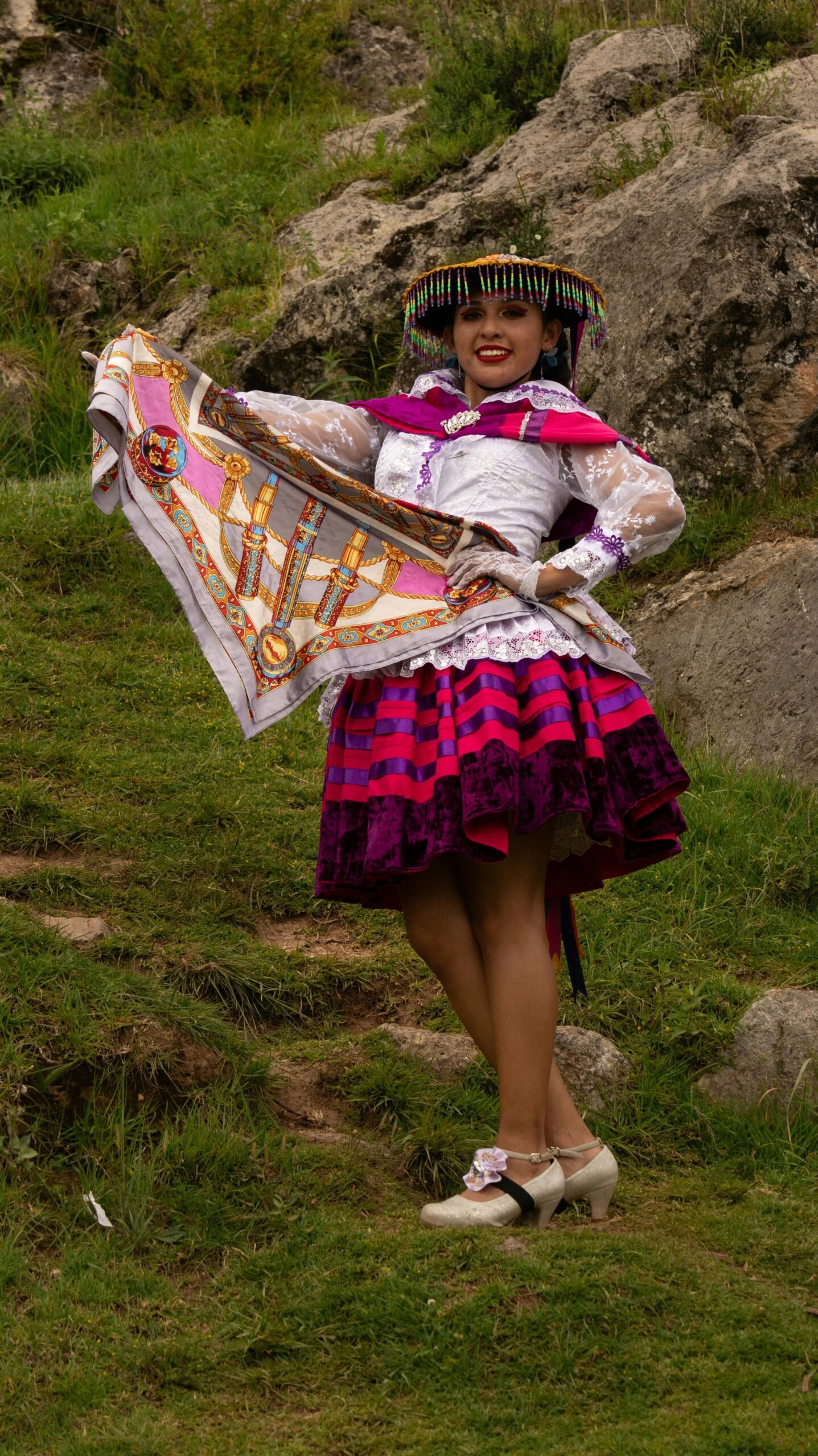 Woman in vibrant traditional dress posing outdoors with colorful attire.